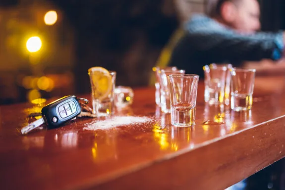 Car keys between shot glasses on a bar counter.