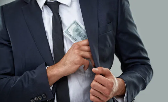 Cropped image of a businessman putting money in his pocket